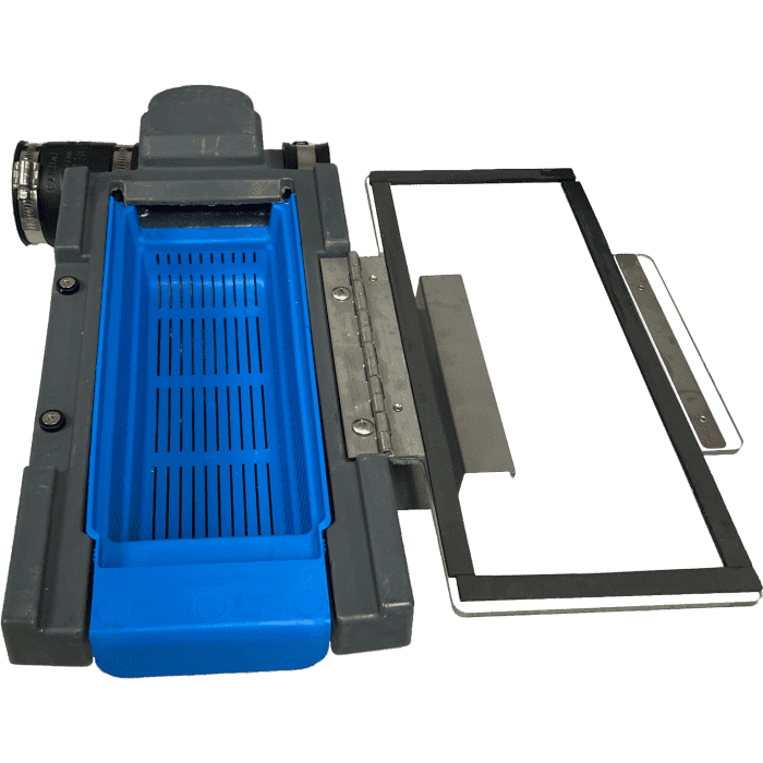 A gray and blue laboratory slide stainer with a removable blue tray, featuring an automatic grease removal system, is shown next to a clear rectangular glass lid attached by a metal hinge. The device is placed on a white background.